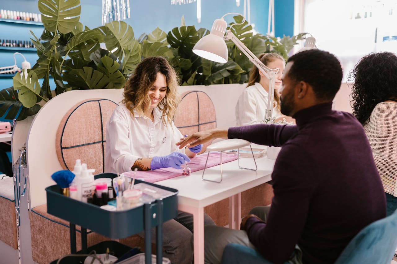 A man getting a professional manicure in a stylish, vibrant nail salon setting.